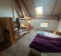 Attic room with a bunk bed, a double bed, and a floor with wooden decor.