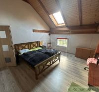 Attic bedroom in a family house with a bed and wooden decor flooring.