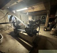 Windows, machines, and tools in the basement of a family house with stone walls.