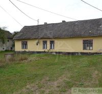 A family house in Nemcovce with a worn-out roof and yellow facade, surrounded by a lawn.