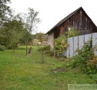 A garden at a family house in Nemcovce with a wooden barn and green lawn.