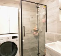 A bathroom with a washing machine, shower, and storage space in a 3-room apartment.