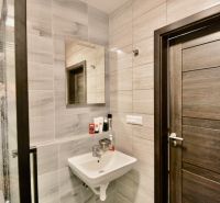 A bathroom with a sink and a mirror in a 3-room apartment, tiles in shades of gray.