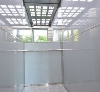 An elevator with reflective panels and a patterned ceiling in a building.