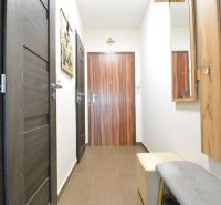 A hallway in a 3-room apartment with tiles, dark doors, and wall decorations.