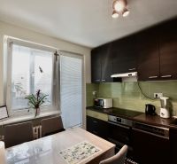A kitchen in a 3-room apartment with dark furniture, green tiles, and appliances.