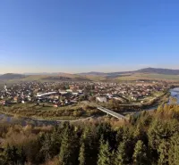 Panorama of agricultural and forest lands in Plavča with a river and a bridge in the background of the forest.