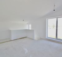 A spacious room in a family house with a large window and a concrete floor.