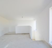 The interior of a family house with an unfinished floor and a large window.
