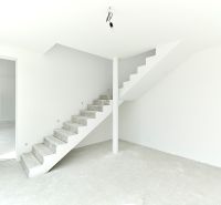 A bright room with unpainted concrete stairs and white walls in a family house.