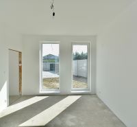 An empty room in a family house with large windows and a view of the garden.