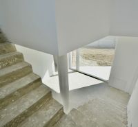 Concrete staircase and light walls in the interior of a family house.