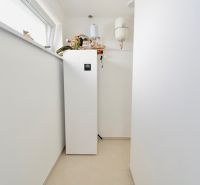 Technical room in a family house with a pump and boiler on white tiles.