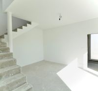 Interior of a family house with a concrete staircase and a large window.