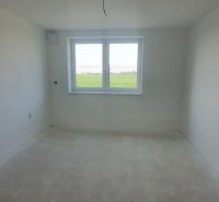 A spacious room in a 3-room apartment with a large window and neutral flooring.