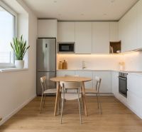 A kitchen with a dining table, light furniture, and a floor with a wood decor in a 3-room apartment.