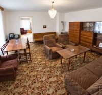A living room in a family house with typical brown furniture and a patterned carpet.