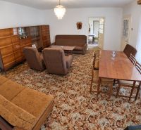 Living room in a family house with carpet pattern, wooden furniture, and a chandelier.