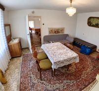 Dining room in a family house with a table, carpet, sofa, and armchairs.