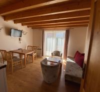 Living room of a holiday apartment with wood-decor flooring and wooden ceiling beams.