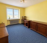 The interior of a family house with wooden furniture, a blue carpet, and yellow walls.