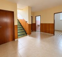 Interior of a family house with tiles, staircase, and wooden wall decor.