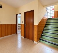 Interior of a family house with a staircase, light flooring, and wooden decor on the walls.