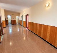 A hallway in a family house with tiles and wooden paneling, further is a bathroom.