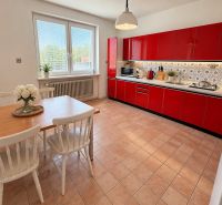 A kitchen in a family house with a red kitchen unit and a dining table for four.