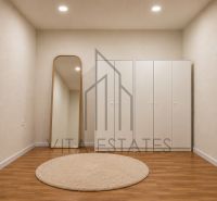 A beige room with wood-patterned flooring, a mirror, and built-in wardrobes in a 3-room apartment.