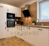 A kitchen with white cabinets and a wood-patterned floor in a 3-room apartment.