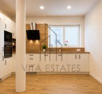 A kitchen of a three-room apartment with a wooden decor floor and built-in appliances.
