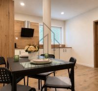 A bright kitchen with a dining table and a wooden decor floor in a 3-room apartment.