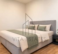 A bedroom with a bed and a wooden decor floor in a three-room apartment.