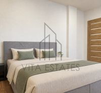 Bedroom with wood-patterned flooring in a 3-room apartment, bed, nightstand, flowers.