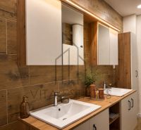 A bathroom with two sinks, wooden decor, a mirror, and storage space in a 3-room apartment.