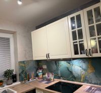 A kitchen with white cabinets and decorative mosaic in a family house.