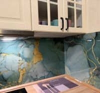 A kitchen in a family house with glass cladding featuring a marble pattern and wooden decor.
