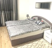 Bedroom in a family house with a gray bed and a floor with a wooden decor.
