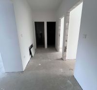 A hallway in a 3-room apartment with thick concrete floors and white walls.