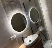 A bathroom in a 2-room apartment with a wooden decorative floor and a modern shower cabin.