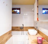 A bathroom in a family house with white tiles and a floor with a wood design.
