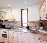 A kitchen in a family house with white cabinets and a tiled wall.