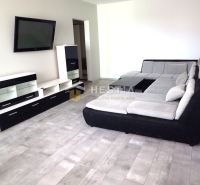 Living room in a 3-room apartment with a gray sofa and a TV on the wall.