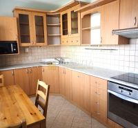 A kitchen in a 3-room apartment, a kitchen unit with a wooden decor, and a dining table.
