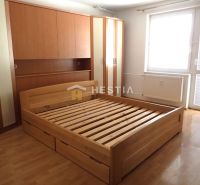 Bedroom in a 3-room apartment with a wooden wardrobe and bed, floor with wooden decor.