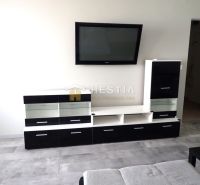 Living room in a three-room apartment with furniture and a TV on the wall.