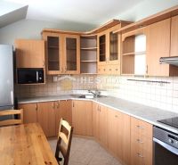 A kitchen in a 3-room apartment with wooden cabinets and a dining table.