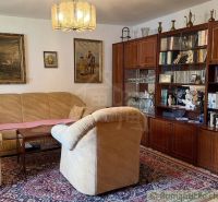 Living room in a family house with furniture, carpet, and paintings on the walls.