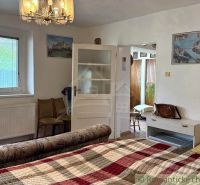 A bedroom in a family house with a comfortable bed, a chandelier, and light-colored walls.